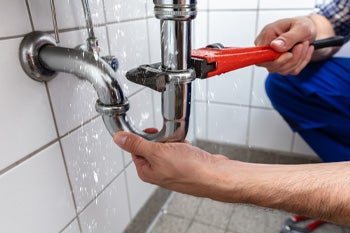 Plumber using a pipe wrench to fix a pipe